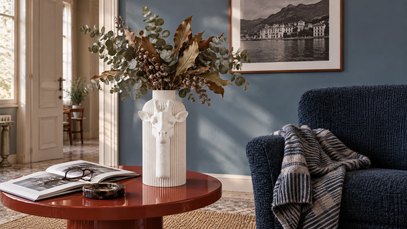 Vaso Giraffa Elegante bianco della White Collection, ambientato accanto a una poltrona blu