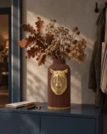 Vaso Rinoceronte Corazzato marrone con decorazione color oro, ambientato con una composizione di rami secchi.