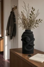 Vaso Serpente Avvolgente nero della Black Collection, ambientato con rami decorativi e foglie secche.