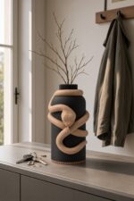 Vaso Serpente Black Creme, corpo nero con decorazione e bordo alla base color crema, ambientato con rami secchi.