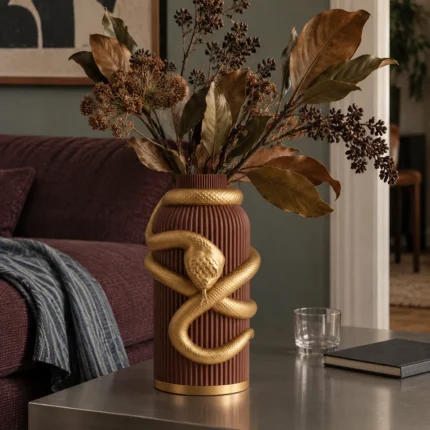 Vaso Serpente Avvolgente marrone con decorazione color oro, ambientato con una composizione di rami secchi.