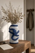 Vaso Serpente con corpo chiaro effetto marmo e decorazione blu notte, della Marble and Blue Collection, ambientato con rami decorativi e foglie secche.