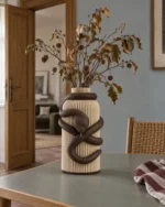 Vaso Serpente marrone e crema della Marrone e Crema Collection, ambientato con rami decorativi e foglie secche.