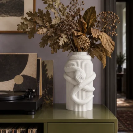Vaso Serpente Avvolgente bianco della White Collection, ambientato con una composizione di rami e foglie secche.